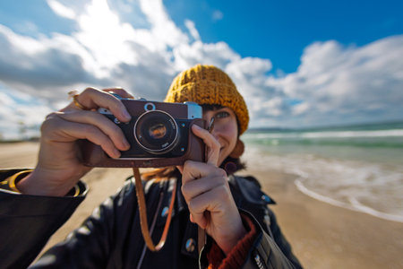 Young girl taking photo outdoors with film camera. Young girl tourist having fun on beach. Lifestyle portrait.の写真素材