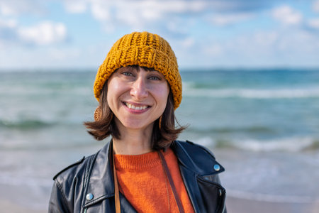 girl smiles. portrait of a girl on the beach. stylish woman in a hat and jacket enjoys going to the...