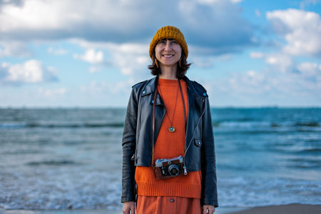 girl with a camera. A stylish and cheerful woman enjoys a walk near the sea on a sunny day. travel...