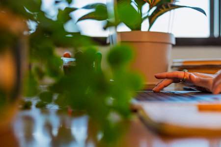 Side view of a girl's hand using a laptop. close-up of a young woman's hands. works remotely, answers emails and completes tasks online. Business concept and online resources.の写真素材