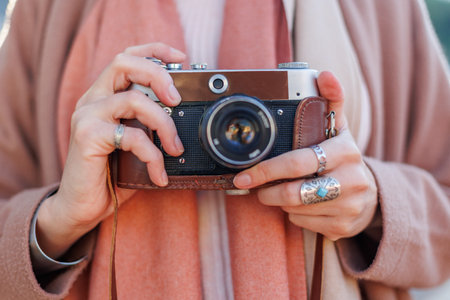 Fashionable look, young woman with film camera. Hipster tourist woman holding a camera in her hands. film camera girl with cameraの写真素材