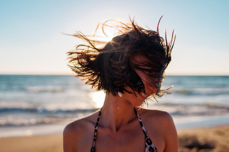 portrait of a beautiful brunette on the beach. Young happy girl smiling. hair covers the face. the wind plays with your hair. Summer tropical mood.の写真素材