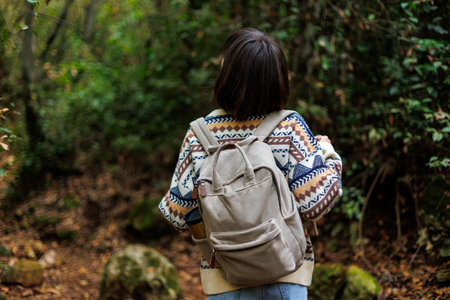 woman in a sweater and a backpack on her back travels. on a hike in the mountains. Adventure and hike. Young happy tourist woman relaxing in natureの写真素材