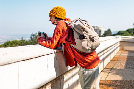 Happy person with a camera. Young tourist sightseeing and walking around the city. Person taking pictures of sights. Person traveling and taking pictures. Tourist walking around the city.の写真素材