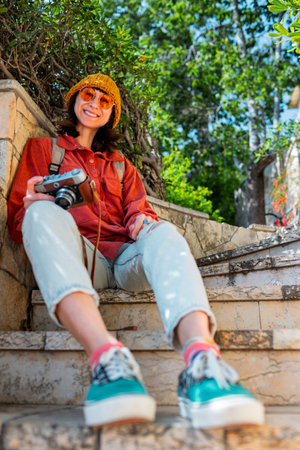 Happy girl with camera. Girl travels and takes pictures. Tourist walks around the city.の写真素材
