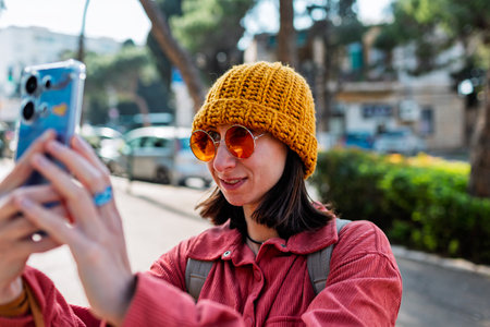 Woman taking photos on the street with a mobile phone. Stylish girl with a phone, tourist in the city.の写真素材
