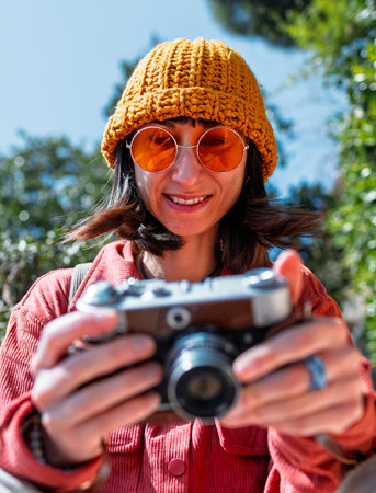 Stylish girl using camera. Urban style and fashion. Tourist with camera walking around the city....