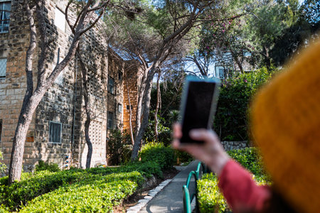 Girl with phone. Young woman taking pictures of flowers on the street. Female hands holding mobile...
