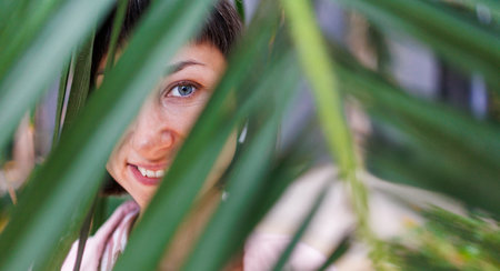 Closeup portrait of a beautiful woman with palm leaf shadows on her face. Natural beauty against the backdrop of tropical leaves. beautiful summer girl behind palm leaves.の写真素材