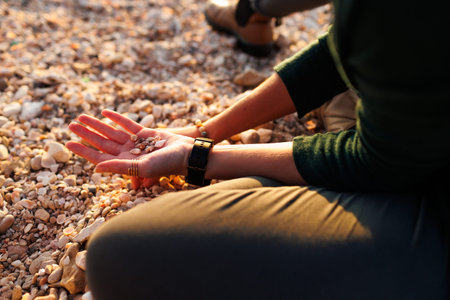 girl relaxing on the beach. a girl sits on the beach and collects various shells in her hand. hands...