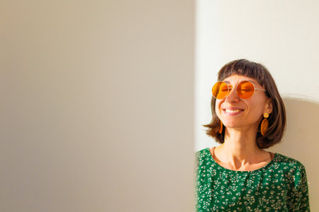 Woman face. Portrait of girl with earrings and sunglasses, smiling at camera, looking confident and cheerful.の写真素材