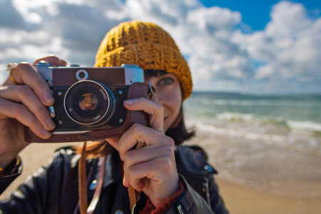 Woman taking photos outdoors. Young beautiful girl taking photos on camera while walking on the beach enjoying her weekend. close up. travel and vacation.の写真素材