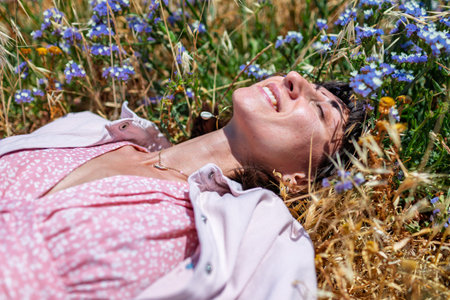 girl enjoying nature. relaxed woman in dress lying on blooming meadow, summer day, feeling nature.の写真素材