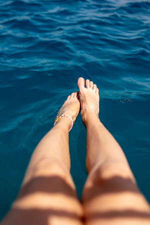 summer mood. Beautiful slender legs of a woman resting in the water, enjoying a summer tan, a woman splashing her legs in the water. a girl resting.の写真素材