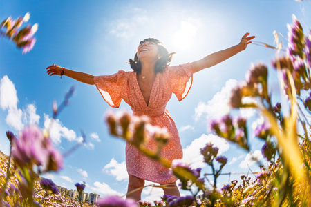 Summer mood. young and cheerful girl in summer dress posing against blue sky and flowers. beautiful girl dancing among flowers. girl enjoying summer. spring fashion.の写真素材