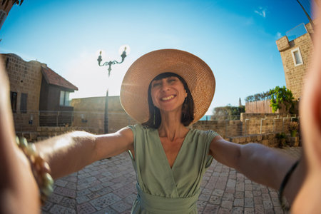 Girl in a beautiful dress and hat traveling. Cute and beautiful fashionable millennial girl taking...