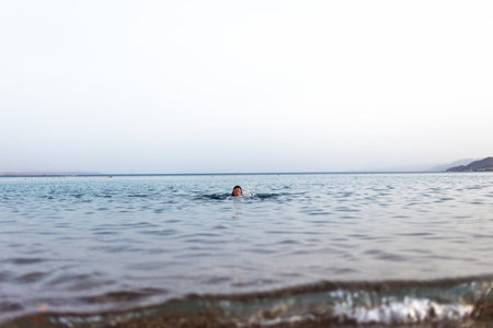 Girl relaxing and swimming in the waters of the Red Sea in Israel. Summer seascape with a girl. Travel and vacation.の写真素材