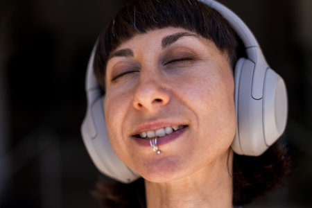 Young woman listening to music on headphones. Stylish girl listening to songs through wireless headphones. Girl in enjoying the song.の写真素材