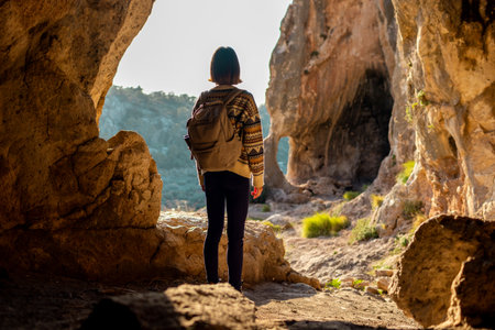 girl with a backpack. A woman with a backpack stands in a cave. The girl explores the cave. Speleologist. Tour of the cave.の写真素材