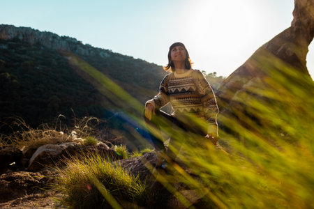 happy woman in the mountains. girl resting sitting on a stone in the mountains. trekking and hiking. concept of sports and healthy lifestyle. girl with a backpack.の写真素材
