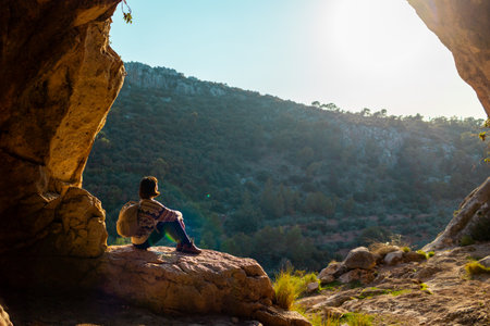 happy woman in the mountains. girl resting sitting on a stone in the mountains. trekking and hiking. concept of sports and healthy lifestyle. girl with a backpack.の写真素材