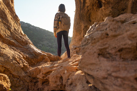 girl with a backpack. A woman with a backpack stands in a cave. The girl explores the cave. Speleologist. Tour of the cave.の写真素材