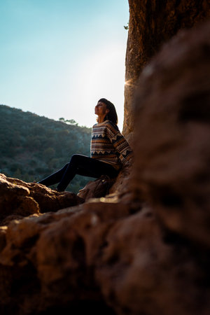 happy woman in the mountains. girl resting sitting on a stone in the mountains. trekking and hiking. concept of sports and healthy lifestyle. girl with a backpack.の写真素材