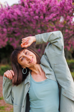 portrait of a happy girl. urban style and fashion. A young brunette smiles happily while walking in a city garden. Young stylish girl in a shirt. Summer portraitの写真素材
