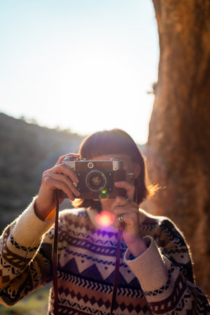 happy woman in the mountains with a camera in her hands enjoying the moment. trekking and hiking. girl with a camera. film cameraの写真素材