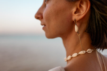 Portrait of a girl on the seashore, earrings and necklaces made of shells. Summer mood. Girl by the sea.の写真素材