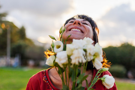 Portrait of smiling woman outdoors with a bouquet of flowers. girl is given a bouquet of flowers. Close-up of young woman, with a romantic mood on a summer evening.の写真素材