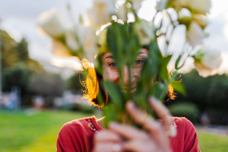 Portrait of smiling woman outdoors with a bouquet of flowers. girl is given a bouquet of flowers. Close-up of young woman, with a romantic mood on a summer evening.の写真素材
