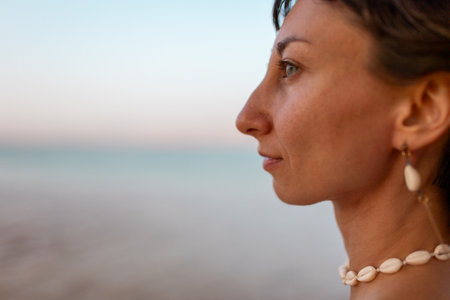 Portrait of a girl on the seashore, earrings and necklaces made of shells. Summer mood. Girl by the sea.の写真素材