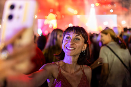 Girl at a concert. cheerful and happy girl taking selfie on phone at summer open air music festival.の写真素材