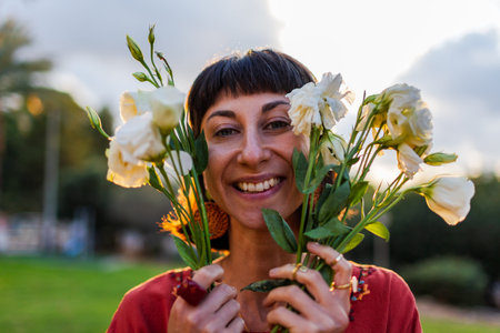 Close up of smiling lady face with bouquet of fresh spring flowers in sunlight. Face of happy girl...