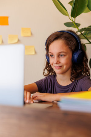 girl in headphones sits in front of laptop at home.