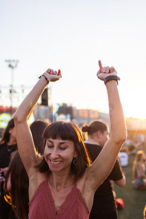 girl at a concert of her favorite music group, dancing and smiling from happiness, celebration and excitement. Young woman dancing at a concert, having fun on an open area. girl dancing.の写真素材