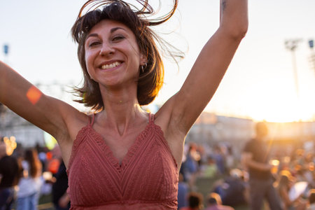girl at a concert of her favorite music group, dancing and smiling from happiness, celebration and excitement. Young woman dancing at a concert, having fun on an open area. girl dancing.の写真素材
