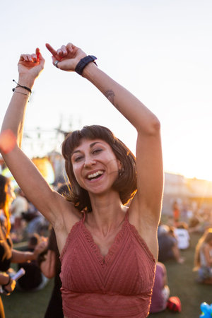 Young woman dancing at concert, having fun at night on open air stage. Sexy woman enjoying music at...