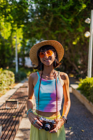 Stylish woman with a camera on the street. Portrait of a beautiful girl smiling on the street....