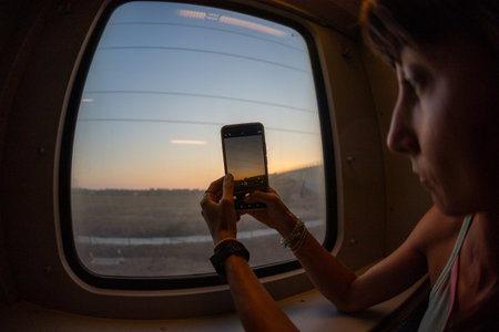 Young woman creating content for social networks. Girl taking photos from the window of a moving...