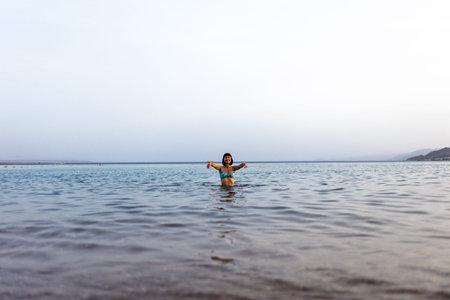 Slender girl in a swimsuit enjoys swimming in the sea. The girl relaxes and swims in the waters of...