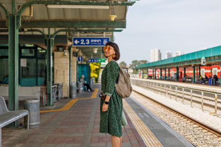 girl looking at watch and waiting for train. girl standing at train station waiting for train....