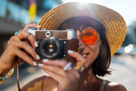Girl with camera traveling and taking pictures. Summer portrait of smiling young woman with camera...