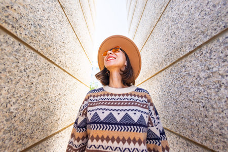 Beautiful girl standing between two walls and smiling. Young beautiful smiling hipster woman in...