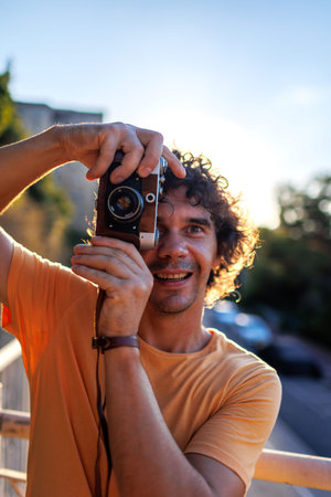 Portrait of a handsome stylish young man in a yellow T-shirt with a camera in his hands. film camera