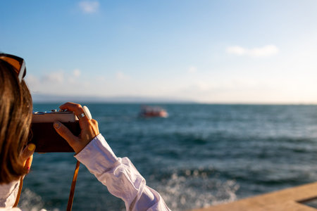 Girl taking pictures. Beautiful tourist enjoying sea view during weekend vacation and taking a...