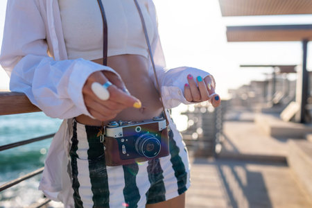 Beautiful tourist enjoying sea view during vacation. film camera Girl with camera. Hobby and...