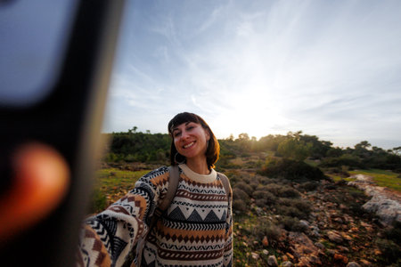 girl takes selfie photo on top of mountain, autumn hike with backpacks. girl travels. selfie photo.の写真素材
