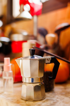 Moka pot on the table at home. Coffee making concept. Moka pot, bean spray, coffee grinder, jar of coffee beans standing on the kitchen table. Ingredients for making coffee.の写真素材